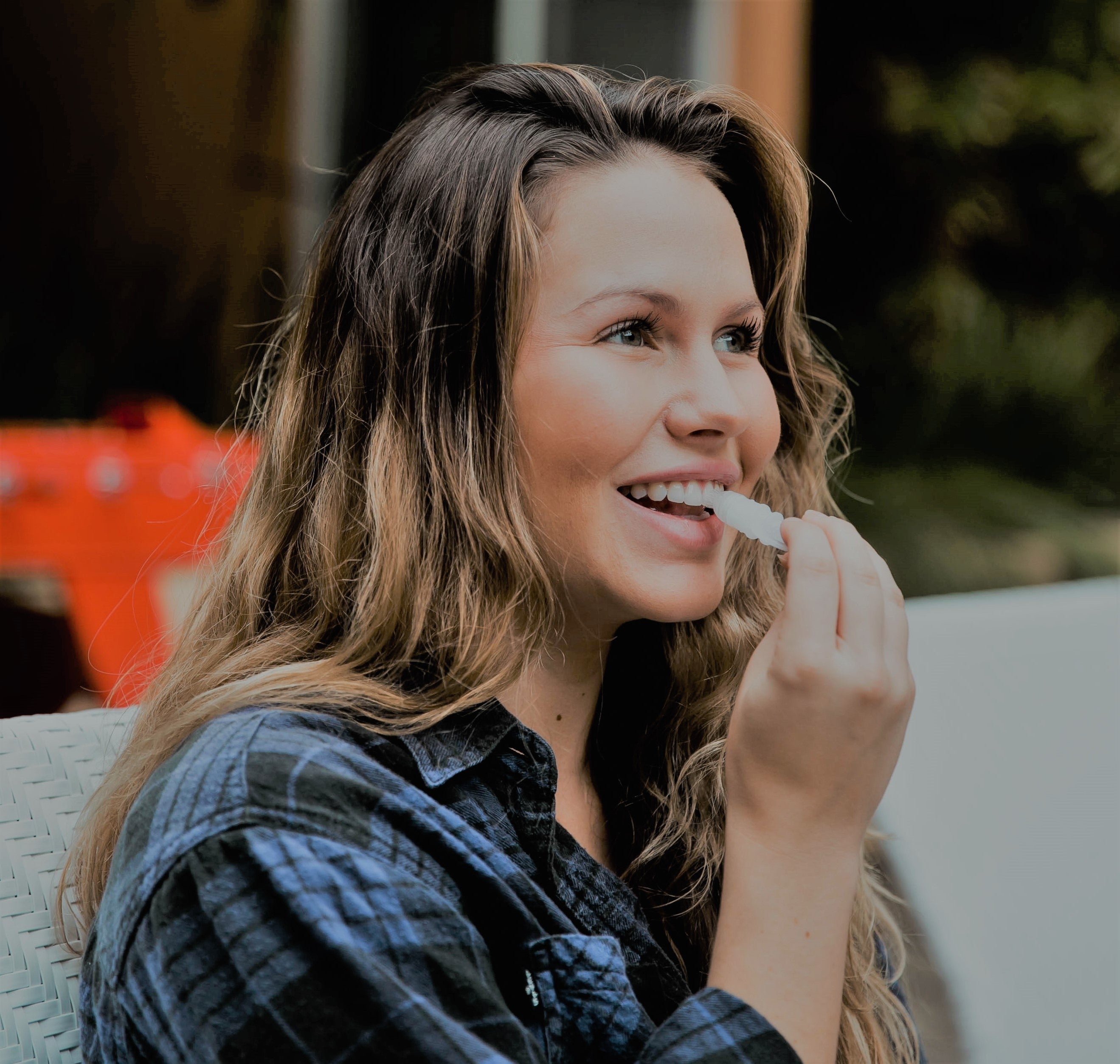 Girl whitening her teeth with a GLO Vial